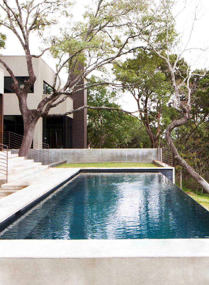 Design ideas for a contemporary rectangular infinity pool in Austin with concrete slab.