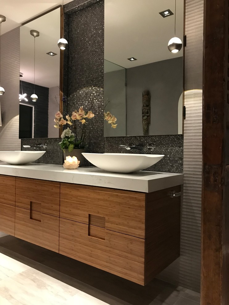 This is an example of a large modern master bathroom in San Francisco with flat-panel cabinets, light wood cabinets, a freestanding tub, a curbless shower, a bidet, gray tile, stone tile, grey walls, porcelain floors, a vessel sink, quartzite benchtops, grey floor, an open shower and white benchtops.