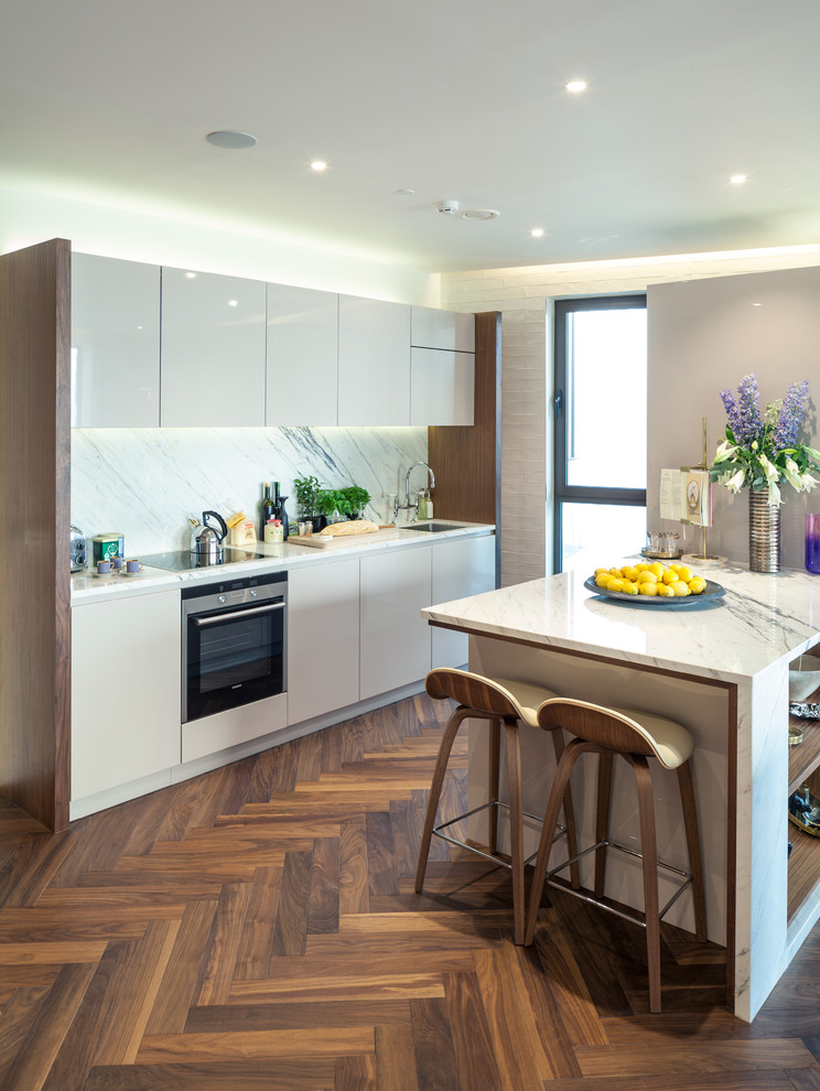 Design ideas for a contemporary kitchen in London with an undermount sink, flat-panel cabinets, white cabinets, white splashback, stainless steel appliances, medium hardwood floors and a peninsula.