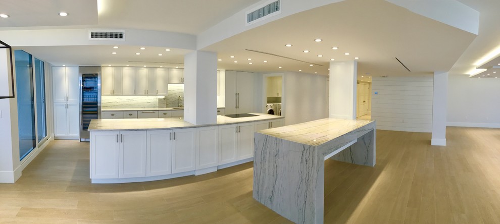 Open concept kitchen - large transitional galley light wood floor and beige floor open concept kitchen idea in Miami with shaker cabinets, white cabinets, an island, an undermount sink, marble countertops, gray backsplash, marble backsplash and stainless steel appliances
