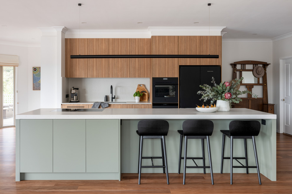Inspiration for a large contemporary kitchen in Sydney with an undermount sink, flat-panel cabinets, green cabinets, quartz benchtops, engineered quartz splashback, black appliances, medium hardwood floors and with island.