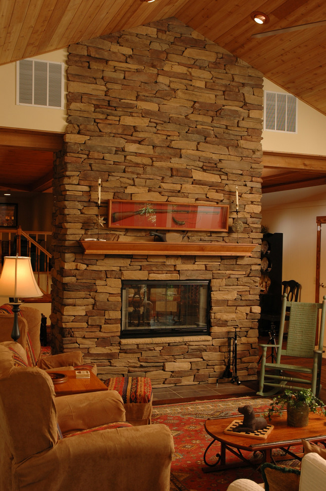 This is an example of a mid-sized arts and crafts open concept living room in Cincinnati with a home bar, beige walls, medium hardwood floors, a two-sided fireplace, a stone fireplace surround and no tv.