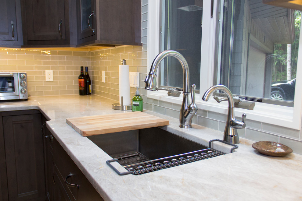 Eat-in kitchen - mid-sized transitional l-shaped light wood floor eat-in kitchen idea with an undermount sink, recessed-panel cabinets, dark wood cabinets, onyx countertops, gray backsplash, glass tile backsplash, stainless steel appliances and an island