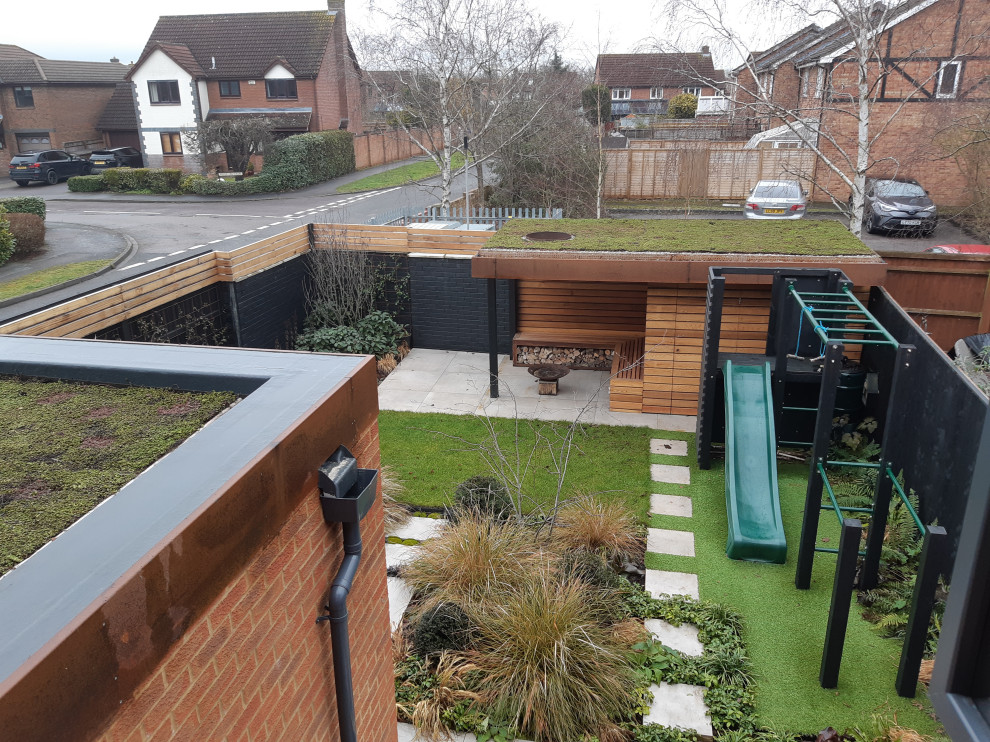 Small contemporary backyard full sun garden in Oxfordshire with with outdoor playset for summer.