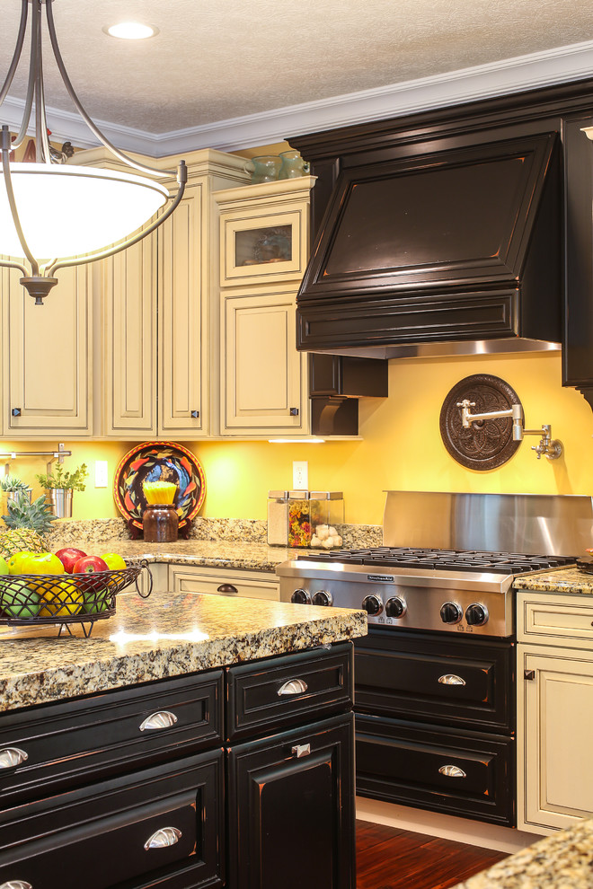 Inspiration for a large transitional l-shaped dark wood floor enclosed kitchen remodel with a double-bowl sink, raised-panel cabinets, beige cabinets, granite countertops, yellow backsplash, stainless steel appliances and an island