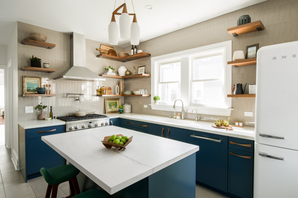 Photo of a mid-sized midcentury l-shaped kitchen pantry in Chicago with an undermount sink, recessed-panel cabinets, blue cabinets, quartz benchtops, beige splashback, ceramic splashback, white appliances, porcelain floors, with island, grey floor and white benchtop.