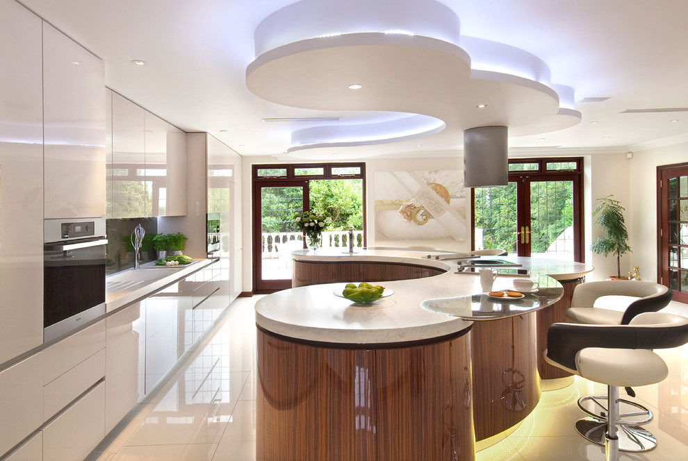 Design ideas for an expansive modern u-shaped eat-in kitchen in London with an integrated sink, flat-panel cabinets, medium wood cabinets, solid surface benchtops, metallic splashback, glass sheet splashback, stainless steel appliances, porcelain floors and with island.