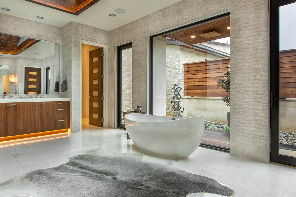 Expansive contemporary master bathroom in Dallas with flat-panel cabinets, medium wood cabinets, a freestanding tub, gray tile, grey walls, grey floor and white benchtops.