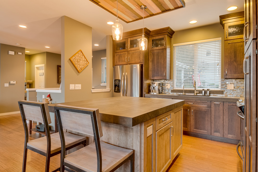 Open concept kitchen - mid-sized transitional l-shaped bamboo floor open concept kitchen idea in Seattle with an undermount sink, flat-panel cabinets, brown cabinets, gray backsplash, mosaic tile backsplash, stainless steel appliances and an island