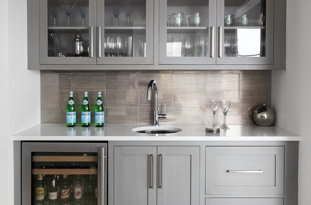 Inspiration for a mid-sized beach style single-wall wet bar in New York with an undermount sink, shaker cabinets, grey cabinets, quartzite benchtops, grey splashback and white benchtop.