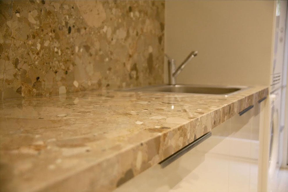 Example of a transitional kitchen design with a drop-in sink, flat-panel cabinets, beige cabinets, quartz countertops, beige backsplash and stone slab backsplash