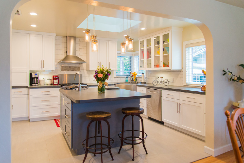 Transitional u-shaped porcelain tile kitchen photo in Sacramento with a farmhouse sink, shaker cabinets, white cabinets, white backsplash, subway tile backsplash, stainless steel appliances and an island