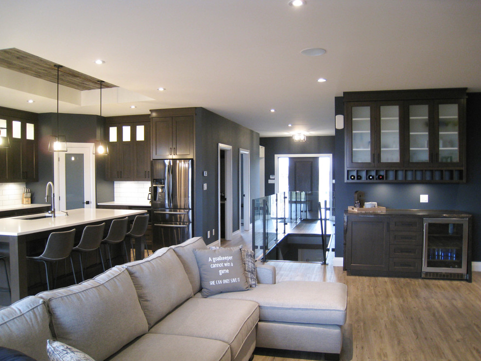 Transitional l-shaped open concept kitchen photo in Toronto with shaker cabinets, dark wood cabinets, quartz countertops, white backsplash, ceramic backsplash, black appliances, an island and white countertops