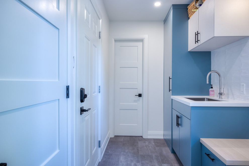 Immagine di un ingresso o corridoio design di medie dimensioni con pareti blu, pavimento con piastrelle in ceramica, una porta singola, una porta bianca e pavimento grigio
