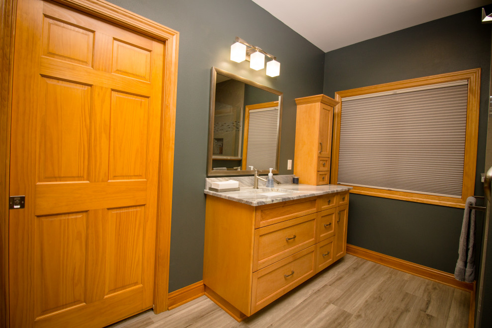 This is an example of a traditional bathroom in Milwaukee with shaker cabinets, medium wood cabinets, an alcove shower, a bidet, porcelain tiles, green walls, vinyl flooring, a submerged sink, granite worktops, a hinged door, multi-coloured worktops, a shower bench, double sinks and a built in vanity unit.