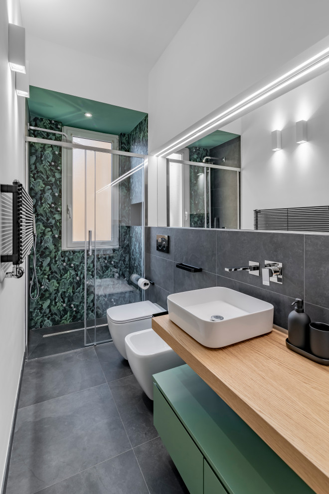 Exempel på ett mellanstort modernt badrum, med släta luckor, gröna skåp, en kantlös dusch, en vägghängd toalettstol, ett fristående handfat, träbänkskiva, svart golv och dusch med skjutdörr