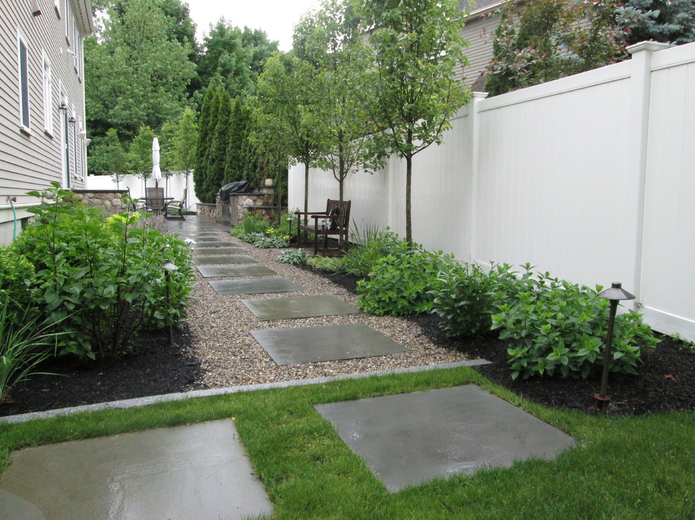 This is an example of a mid-sized contemporary side yard garden in Boston with natural stone pavers.