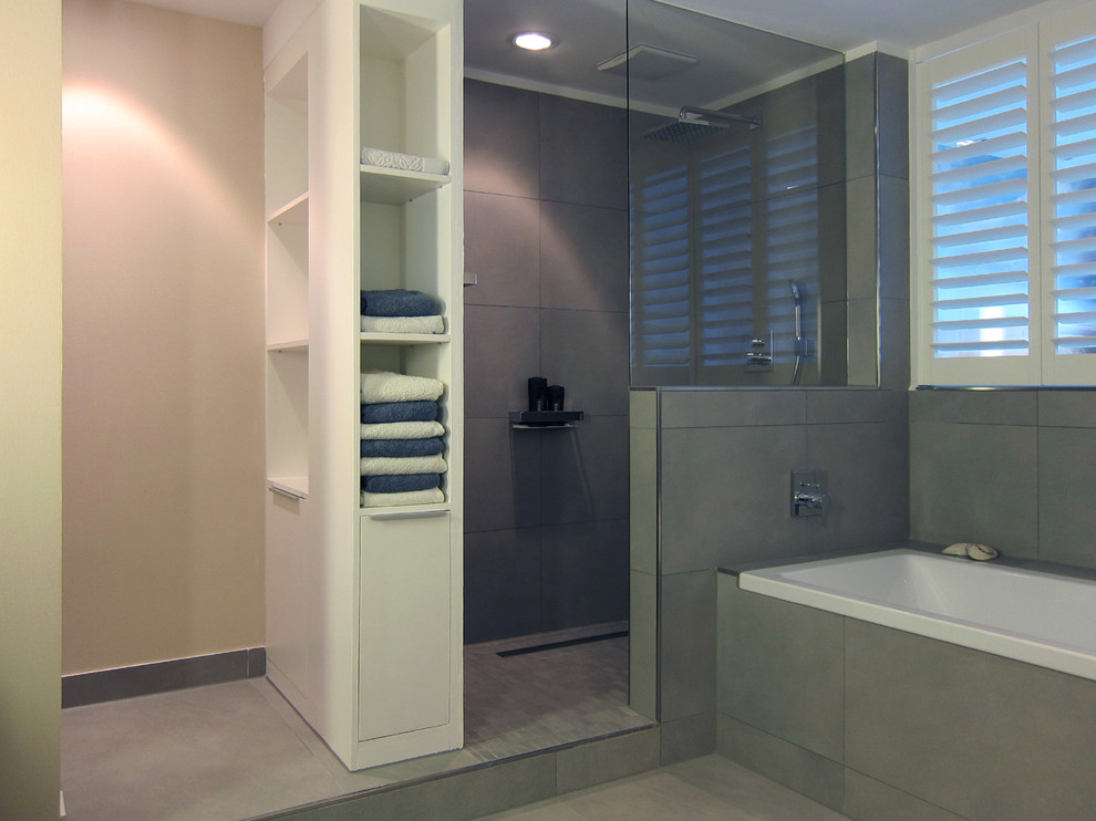 This is an example of a contemporary bathroom in Cologne with a vessel sink, wood benchtops, a drop-in tub, a curbless shower, a wall-mount toilet, gray tile, ceramic tile and ceramic floors.