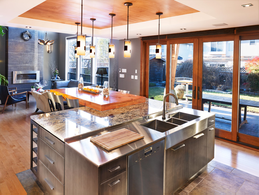 This is an example of an eclectic l-shaped open plan kitchen in Vancouver with flat-panel cabinets, distressed cabinets, stainless steel appliances and with island.