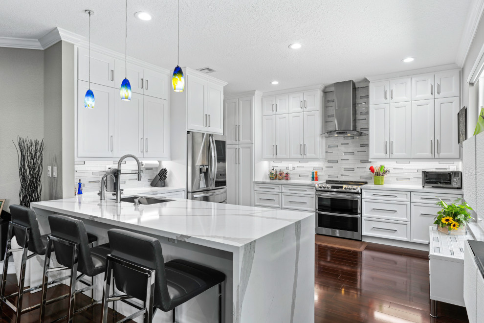 Kitchen - transitional u-shaped dark wood floor and brown floor kitchen idea in Miami with an undermount sink, recessed-panel cabinets, white cabinets, white backsplash, stainless steel appliances, a peninsula and white countertops
