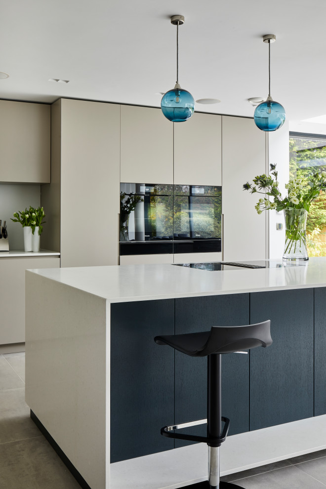 Large contemporary l-shaped open plan kitchen in Kent with flat-panel cabinets, beige cabinets, quartz benchtops, with island and white benchtop.