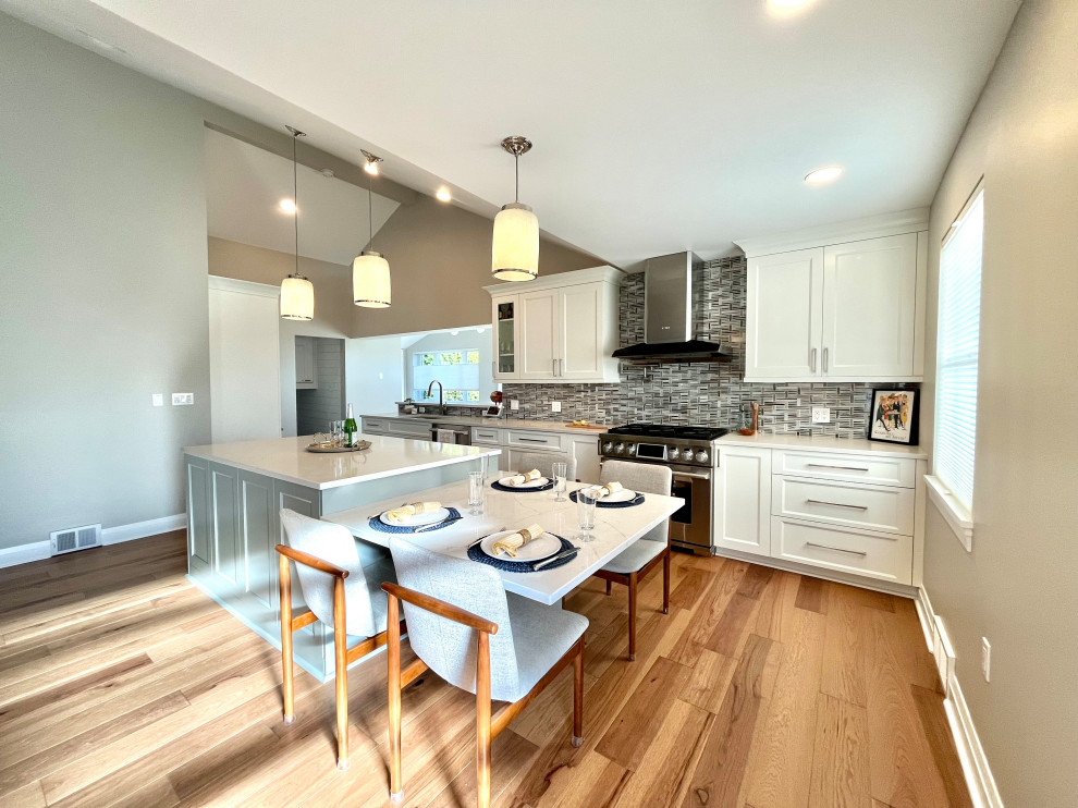 Eat-in kitchen - transitional single-wall vinyl floor, brown floor and vaulted ceiling eat-in kitchen idea with an undermount sink, shaker cabinets, white cabinets, quartz countertops, blue backsplash, glass sheet backsplash, stainless steel appliances, an island and gray countertops