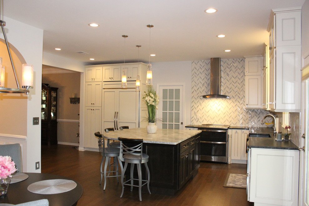 Inspiration for a mid-sized transitional l-shaped dark wood floor and brown floor eat-in kitchen remodel in New York with a farmhouse sink, recessed-panel cabinets, white cabinets, solid surface countertops, white backsplash, cement tile backsplash, stainless steel appliances and an island
