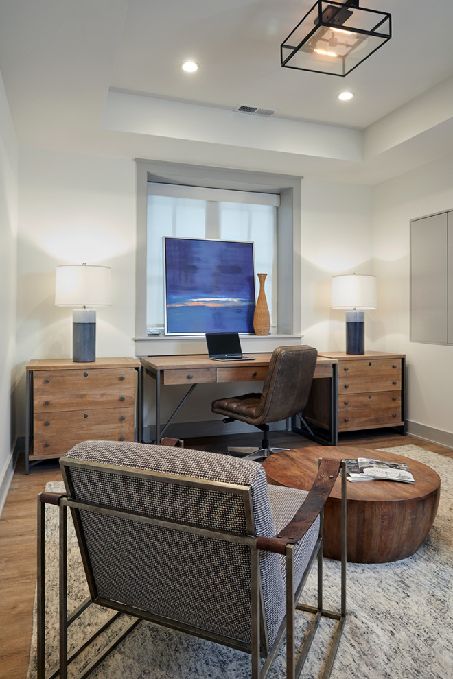 This is an example of a modern home office in Chicago with white walls, light hardwood floors and recessed.
