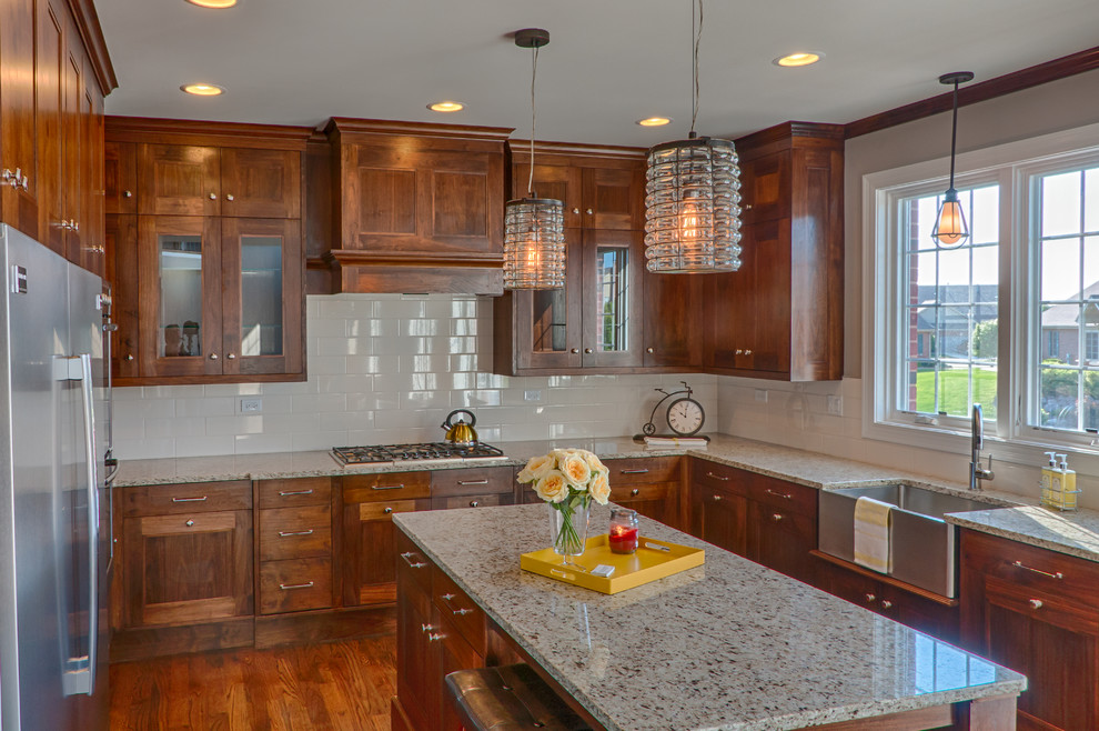 Example of a mid-sized transitional u-shaped dark wood floor eat-in kitchen design in Chicago with a farmhouse sink, recessed-panel cabinets, medium tone wood cabinets, granite countertops, ceramic backsplash, stainless steel appliances, an island and beige backsplash