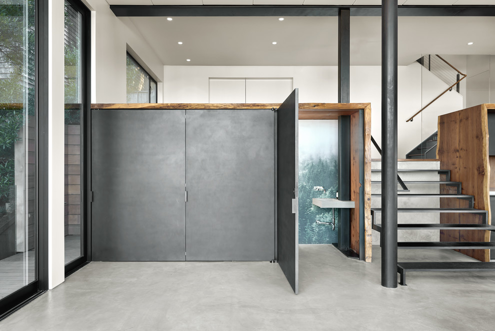 This is an example of a small modern powder room in San Francisco with open cabinets, a wall-mount toilet, black walls, concrete floors, a trough sink, concrete benchtops and grey floor.