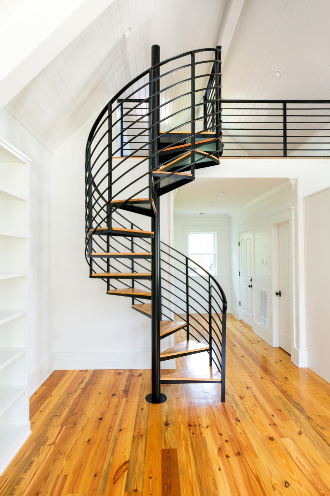 Photo of a small beach style wood spiral staircase in Charleston with open risers and metal railing.