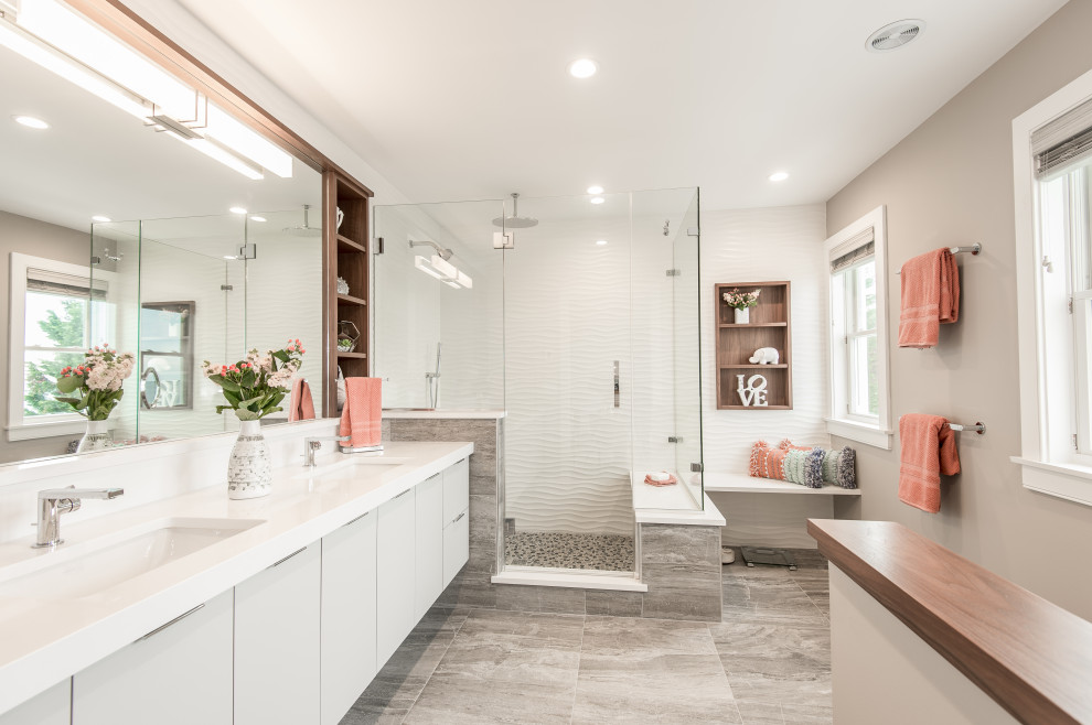 This is an example of a large contemporary master bathroom in Bridgeport with flat-panel cabinets, grey cabinets, a corner shower, white tile, ceramic tile, beige walls, ceramic floors, an undermount sink, engineered quartz benchtops, a hinged shower door, white benchtops and grey floor.