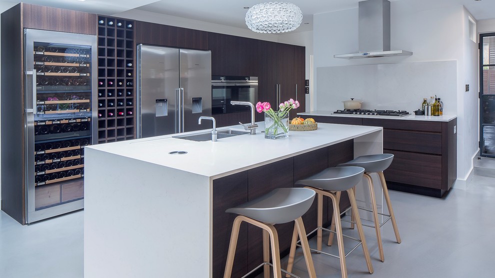 Large contemporary single-wall eat-in kitchen in London with limestone benchtops, a single-bowl sink, white splashback, glass sheet splashback, stainless steel appliances, concrete floors, with island and white floor.
