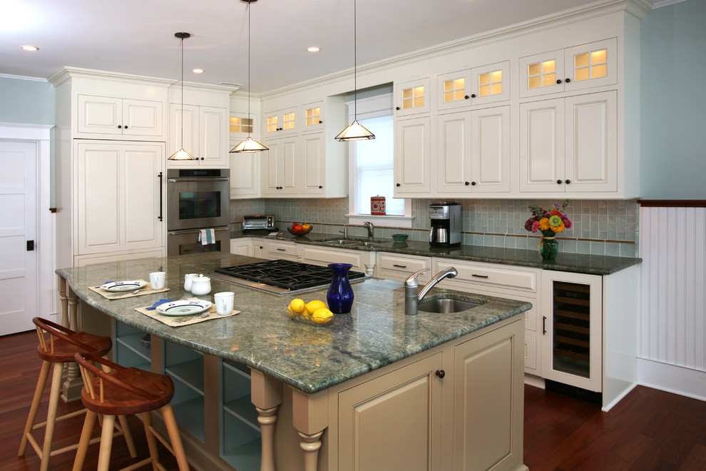 Beach style l-shaped kitchen in Philadelphia with an undermount sink, raised-panel cabinets, white cabinets, green splashback, subway tile splashback and stainless steel appliances.