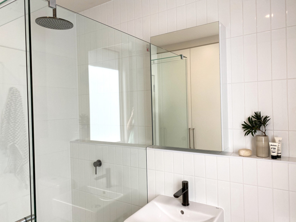 Réalisation d'une petite salle de bain design avec une douche d'angle, un carrelage blanc, un carrelage métro, un sol en carrelage de porcelaine, un lavabo suspendu, un sol marron, une cabine de douche à porte battante et meuble simple vasque.