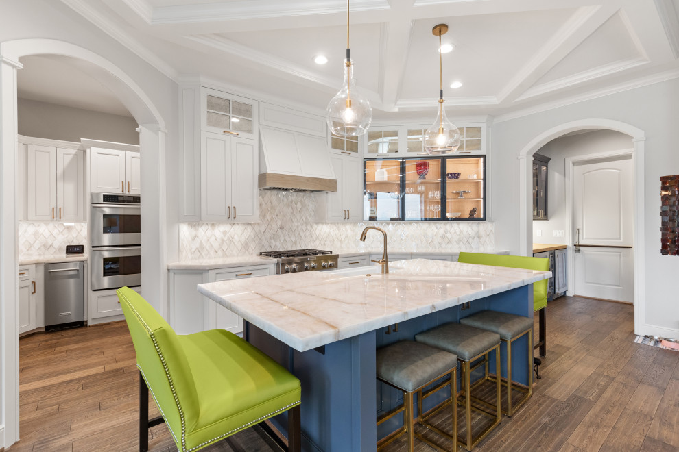 Eat-in kitchen - large transitional single-wall light wood floor and brown floor eat-in kitchen idea in Houston with a farmhouse sink, recessed-panel cabinets, white cabinets, quartzite countertops, white backsplash, mosaic tile backsplash, stainless steel appliances, an island and white countertops