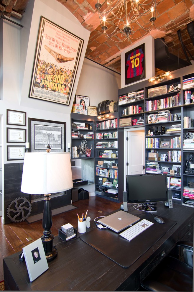This is an example of a mid-sized industrial study room in Chicago with white walls, medium hardwood floors, a metal fireplace surround and a freestanding desk.