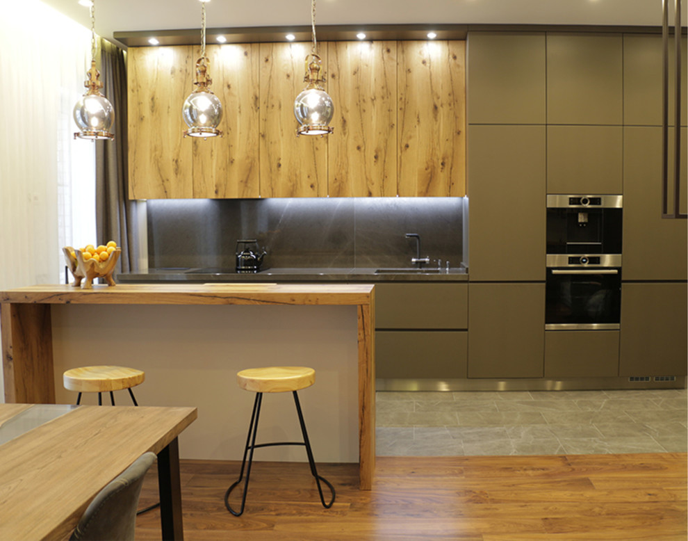 Mid-sized industrial single-wall eat-in kitchen in Moscow with an integrated sink, flat-panel cabinets, green cabinets, solid surface benchtops, brown splashback, black appliances, medium hardwood floors, with island, brown floor and brown benchtop.