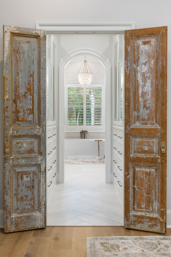 Immagine di una grande camera matrimoniale con pareti bianche, pavimento in legno massello medio e pavimento marrone