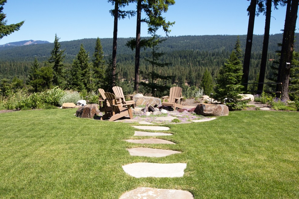 This is an example of a rustic full sun backyard stone landscaping in Seattle with a fire pit.