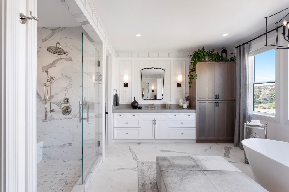 Inspiration for a large transitional master bathroom in Los Angeles with shaker cabinets, white cabinets, a freestanding tub, a bidet, white tile, porcelain tile, white walls, porcelain floors, an undermount sink, engineered quartz benchtops, white floor, grey benchtops, a double vanity and a built-in vanity.