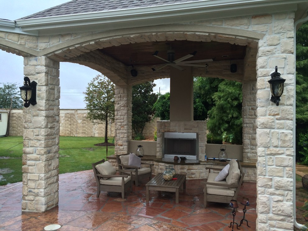 Photo of a contemporary backyard patio in Houston with a fire feature, natural stone pavers and a roof extension.