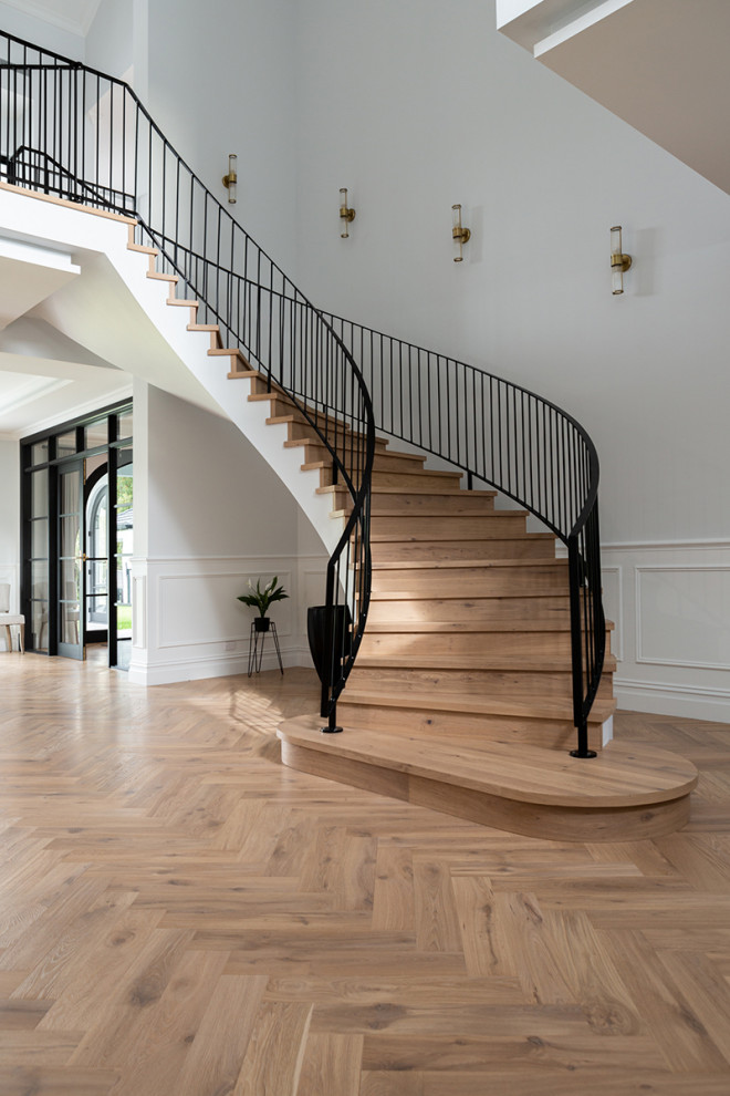Diseño de escalera curva contemporánea con escalones de madera, contrahuellas de madera y barandilla de metal
