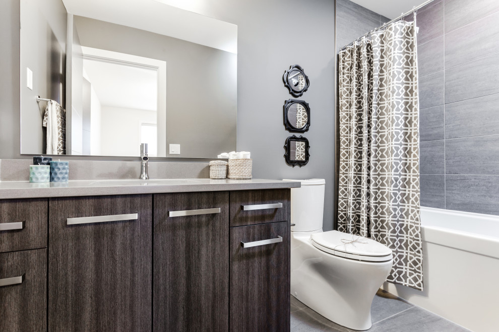 Exempel på ett litet klassiskt grå grått badrum med dusch, med släta luckor, skåp i mörkt trä, en toalettstol med hel cisternkåpa, grå kakel, grå väggar, ett undermonterad handfat och bänkskiva i kvarts