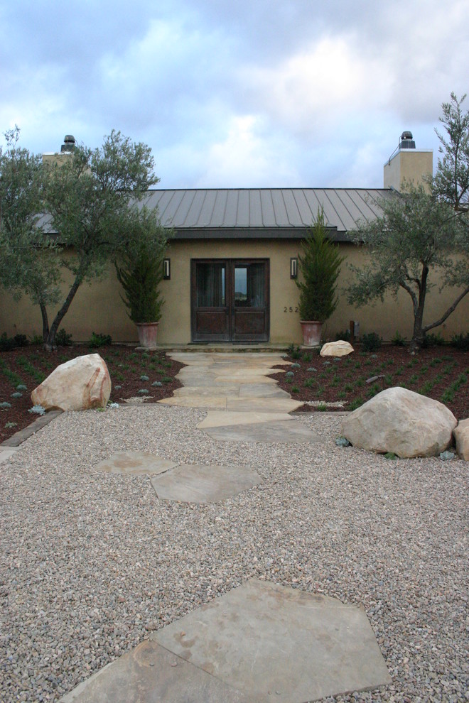 Contemporary full sun xeriscape in Santa Barbara with gravel and with rock feature.