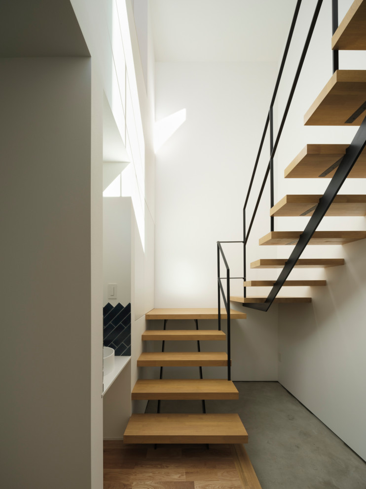 Moderne Holztreppe in U-Form mit offenen Setzstufen, Stahlgeländer und Tapetenwänden in Tokio