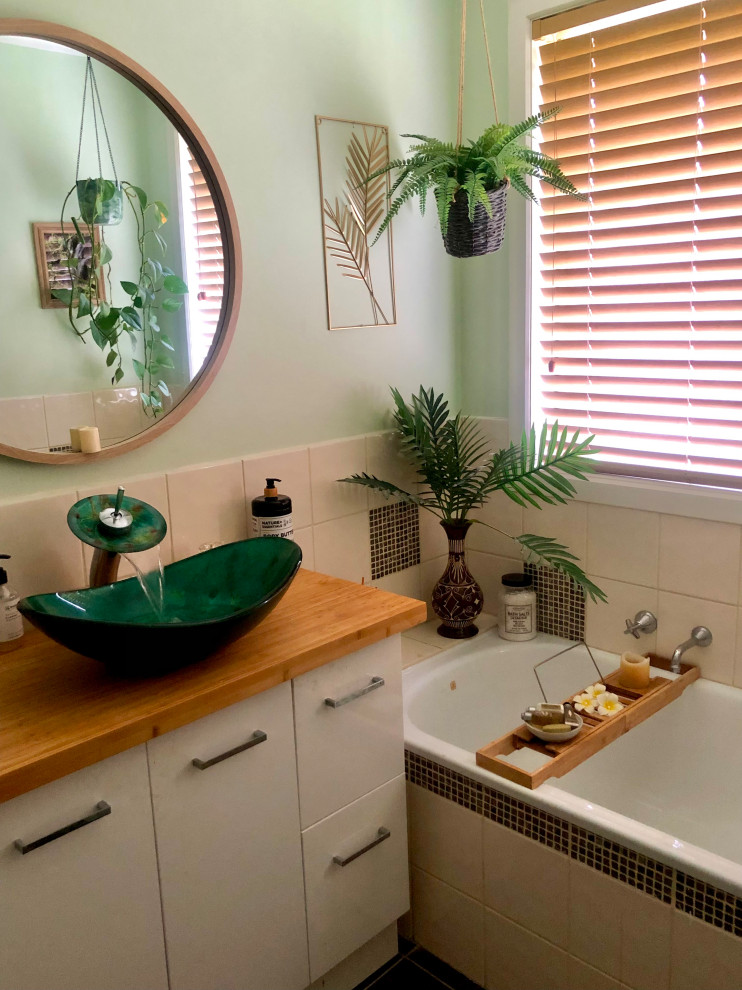 Ispirazione per una stanza da bagno con doccia tropicale di medie dimensioni con ante in legno scuro, vasca da incasso, piastrelle beige, pareti verdi, top in legno, un lavabo e mobile bagno freestanding