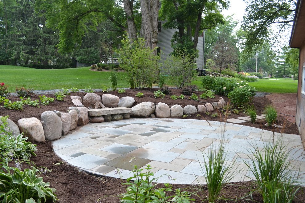 Inspiration for a mid-sized rustic backyard stone landscaping in Milwaukee.