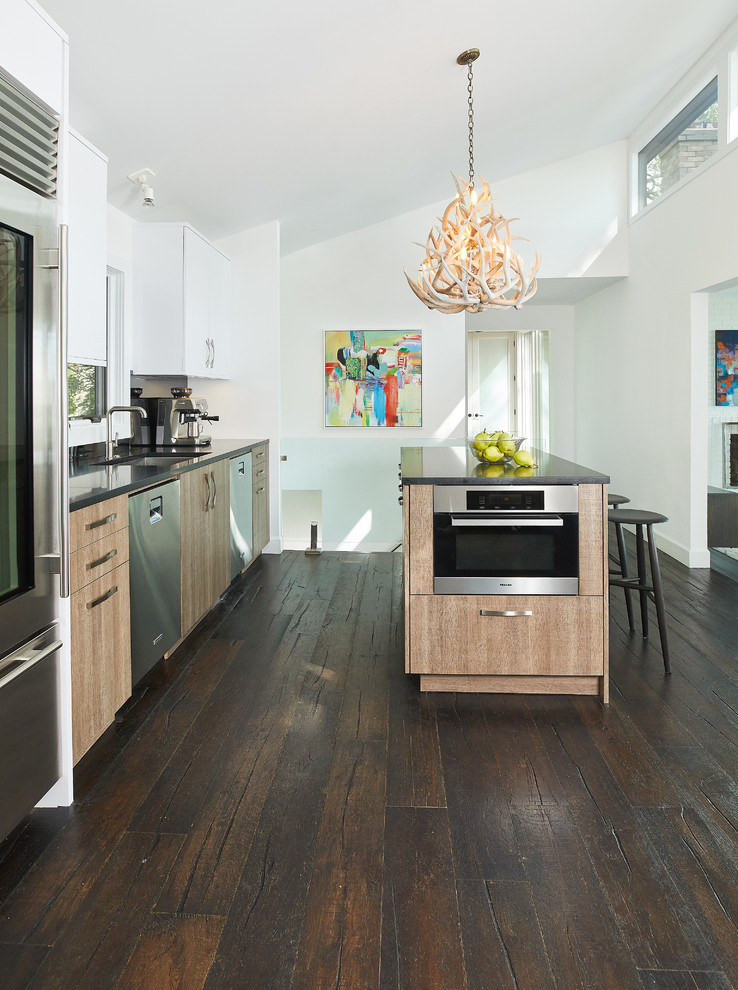 Design ideas for a contemporary galley kitchen in Grand Rapids with an undermount sink, flat-panel cabinets, medium wood cabinets, stainless steel appliances, dark hardwood floors, with island, brown floor and grey benchtop.