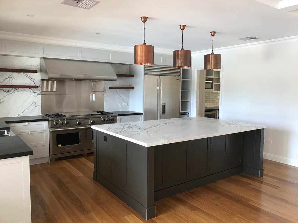 This is an example of a small contemporary l-shaped open plan kitchen in Wollongong with a double-bowl sink, white cabinets, marble benchtops, white splashback, cement tile splashback, stainless steel appliances, medium hardwood floors and with island.